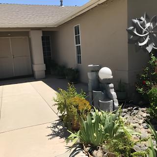 A modern house exterior featuring a well-maintained garden with various plants and a sculpture by the entrance.