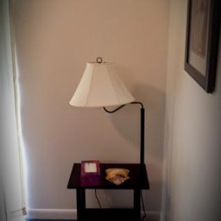 A cozy corner featuring a lamp and a small table.