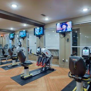 A modern gym with exercise bikes and television screens.