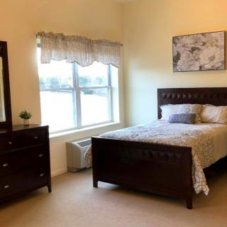 A cozy bedroom with a bed, dresser, and window.