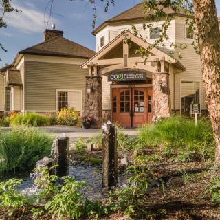 A beautifully landscaped restaurant entrance with a small pond and lush greenery.