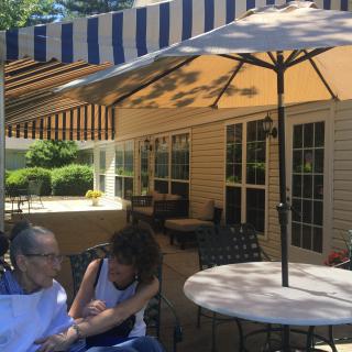 Two people enjoying a sunny day on a shaded patio.
