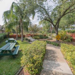 A tranquil garden with a picnic bench, surrounded by lush greenery and a pathway leading through the landscape.