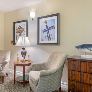 A cozy living room corner with two chairs, a side table with a lamp, and framed artwork on the wall.