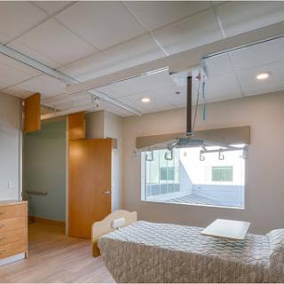 A modern hospital patient room featuring ample natural light and a minimalist design.