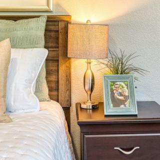 Cozy bedroom scene with a bedside table, lamp, and a photo frame.