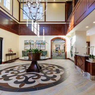 A luxurious lobby with a grand chandelier, elegant furniture, and decorative tile flooring.