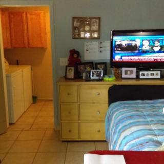 A bedroom with a television on a dresser, adjacent to a laundry room entrance.