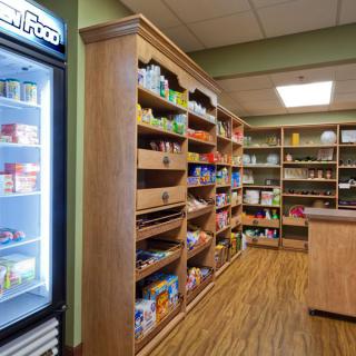 A small grocery store with shelves stocked with various products and a refrigerator.