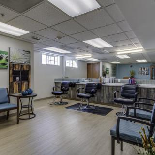 A well-lit hair salon with multiple styling chairs and mirrors, featuring a comfortable waiting area.