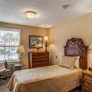 A cozy bedroom with a single bed, traditional wooden furniture, and warm lighting.