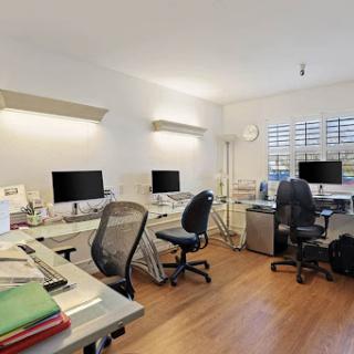 A modern office space featuring multiple workstations equipped with computers and ergonomic chairs.