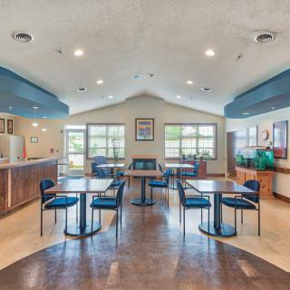 A modern dining area with blue accents, featuring tables and chairs under bright lighting.