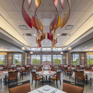 A modern restaurant dining area with stylish chandeliers and neatly arranged tables and chairs.