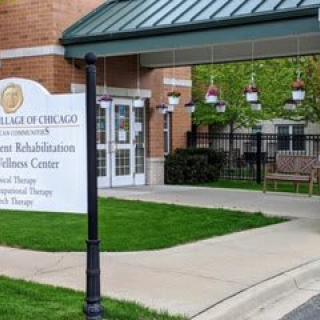 Entrance to a rehabilitation and wellness center with a sign and well-maintained landscaping.