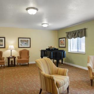 A cozy living room with comfortable seating and a grand piano by the window.