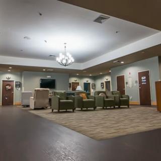 A spacious waiting room with several green chairs and a reception desk.