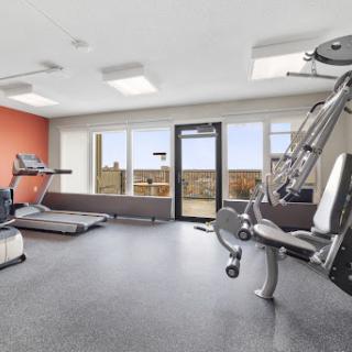 A modern gym space equipped with a treadmill and weight machine, featuring large windows that provide a scenic view.