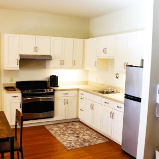 A cozy, modern kitchen featuring white cabinetry and stainless steel appliances, perfect for cooking and dining.