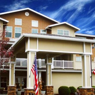 A multi-story residential building with an entrance covered by a large overhang, adorned with national flags.