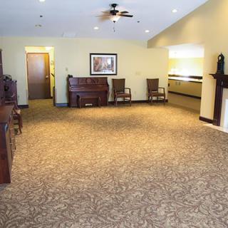 Spacious living room with a piano, chairs, and a fireplace.