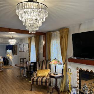 A cozy living room featuring elegant chandeliers, stylish furniture, and a warm fireplace.