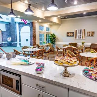 A cozy cafe interior with tables and chairs, featuring a display of assorted pastries on the counter.