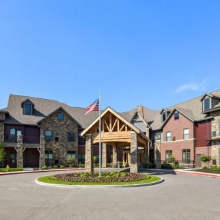 A beautiful residential building with a stone facade and a welcoming entrance, featuring a flagpole in front.