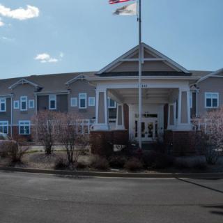 A two-story building with a prominent entrance and flagpole under a bright sky.