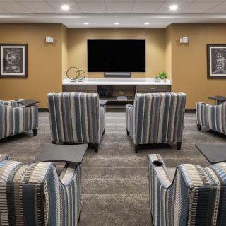 A cozy home theater room with striped upholstered chairs arranged in rows facing a large flat-screen TV.
