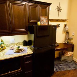 A cozy kitchen corner with dark wooden cabinets and a compact refrigerator.