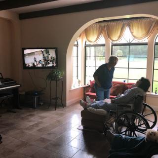 A cozy living room with a television and two people interacting, one seated in a wheelchair.