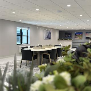 A modern meeting room equipped for discussions and presentations, featuring a large table surrounded by chairs and decorated with plants.