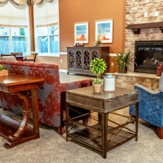 A cozy living room with warm colors, featuring a fireplace, comfortable seating, and decorative elements.