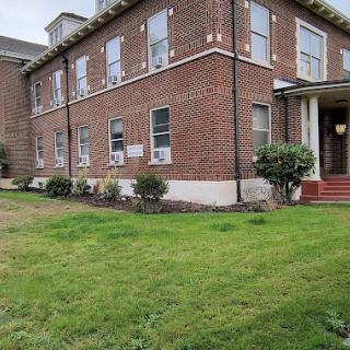 A brick building with well-maintained grass and an inviting entrance.