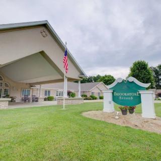 A view of a building with a sign on the lawn and an American flag pole in front.