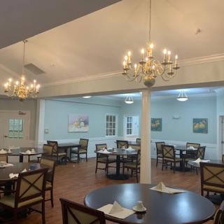 A cozy dining room with elegant chandeliers and neatly arranged tables and chairs.