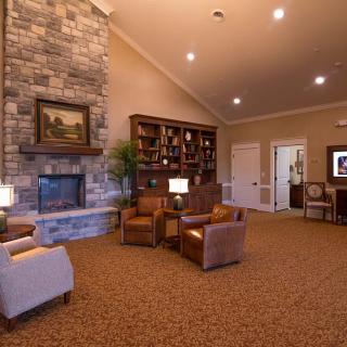 A cozy living room with a stone fireplace, bookshelf, and comfortable armchairs.