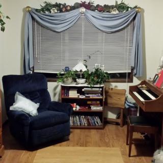 Cozy living room corner with a recliner, bookshelf, and piano.