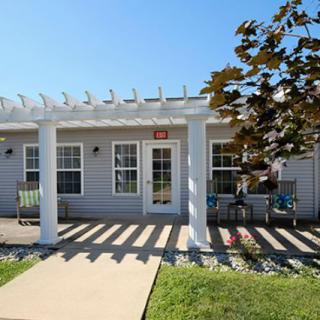 A cozy house with a pergola-covered patio and a well-maintained front yard under a clear blue sky.