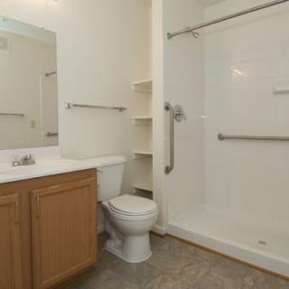 A modern bathroom with a shower, toilet, and sink.