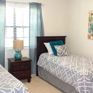 A cozy bedroom featuring twin beds with patterned bedding and a bedside table with a lamp.
