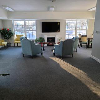 A cozy living room area with armchairs, a television, and large windows allowing natural light to fill the space.