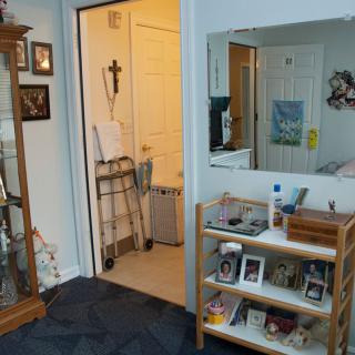 A cozy living space with shelves, a mirror, and a walker nearby.