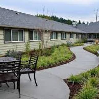 Outdoor seating area along a landscaped pathway in front of a residential building.