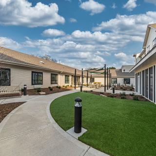 A beautifully landscaped courtyard with a neatly trimmed lawn and modern buildings under a partly cloudy sky.