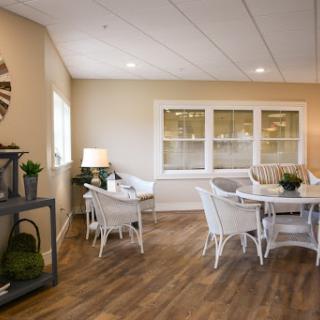 A welcoming and modern dining area featuring white furniture and warm wood flooring, illuminated by natural light.