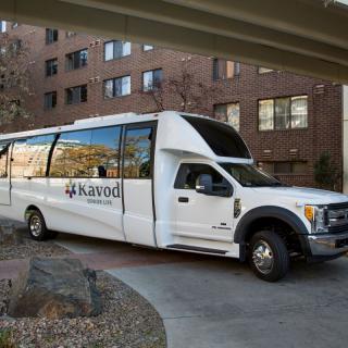A white shuttle bus parked in front of a building.