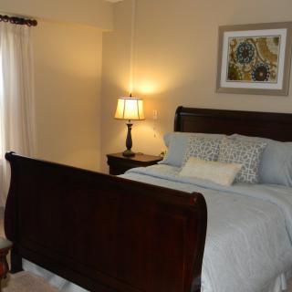 A cozy bedroom with a wooden bed, bedside lamp, and decorative artwork.