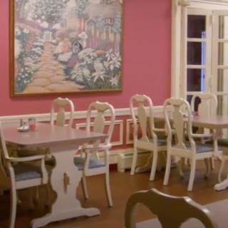 A classic dining room with elegant chairs and a decorative painting on a pink wall.